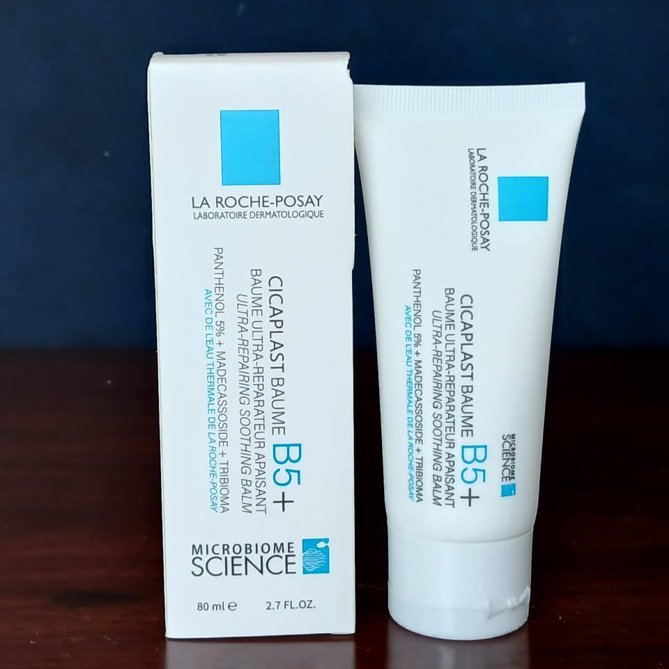 La Roche-Posay Cicaplast Baume B5+ cream and packaging on a dark surface with a blue background
